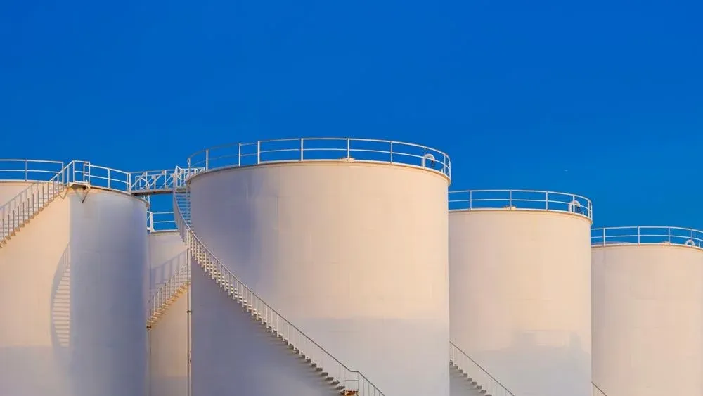 White storage tanks with spiral stairs against a blue sky at Jeddah