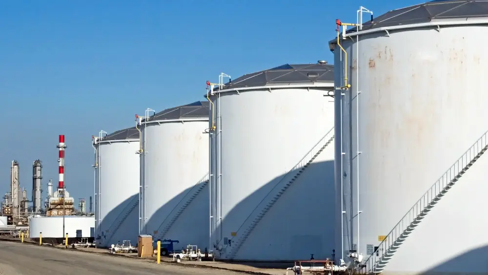 Row of white fuel storage tanks with external stairs under a clear sky at Paphos
