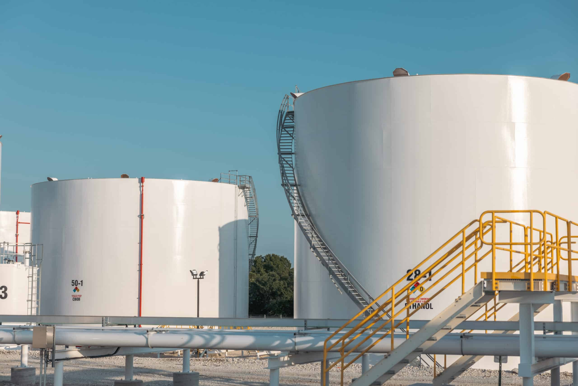 Close-up of white storage tanks with access stairs and pipework at a Houston terminal
