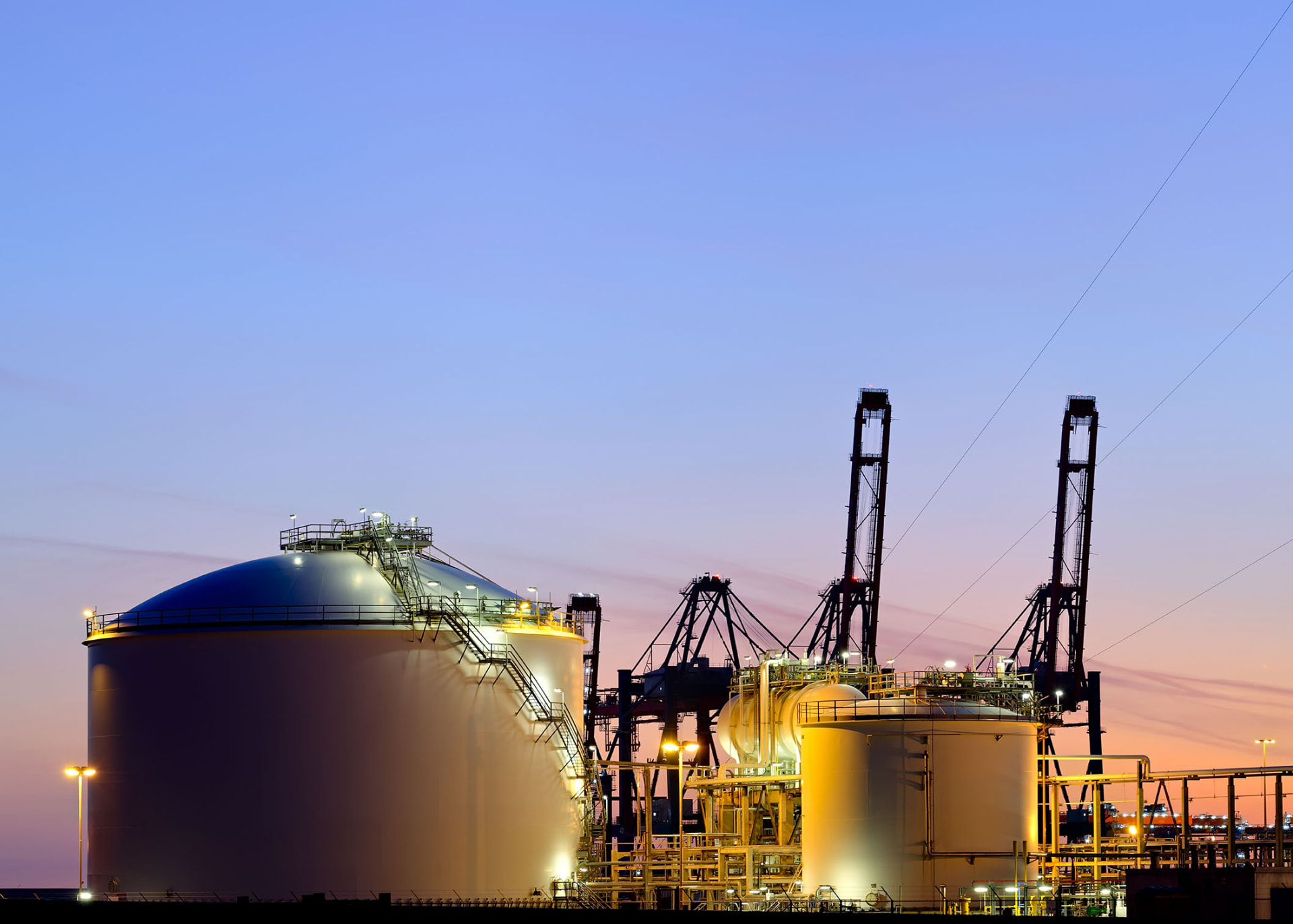 Storage tanks and harbour cranes lit at dusk at Paphos