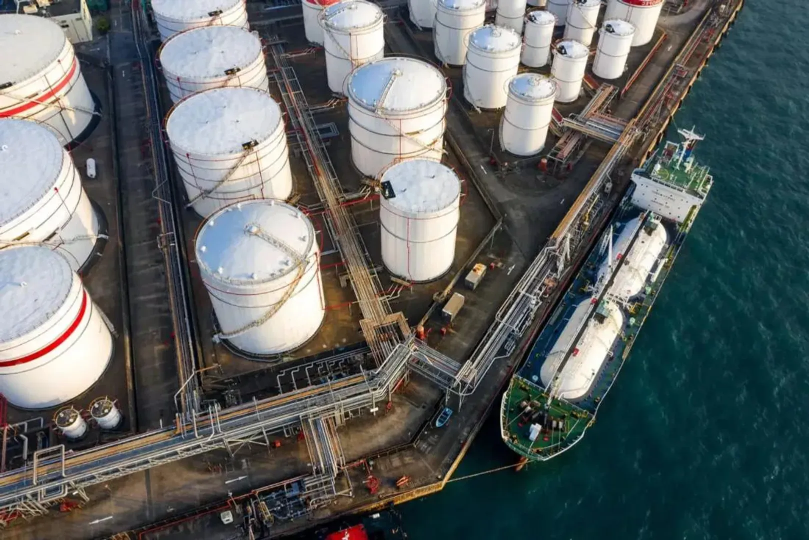 Aerial view of waterfront storage tanks and a berthed vessel at Khorfakkan