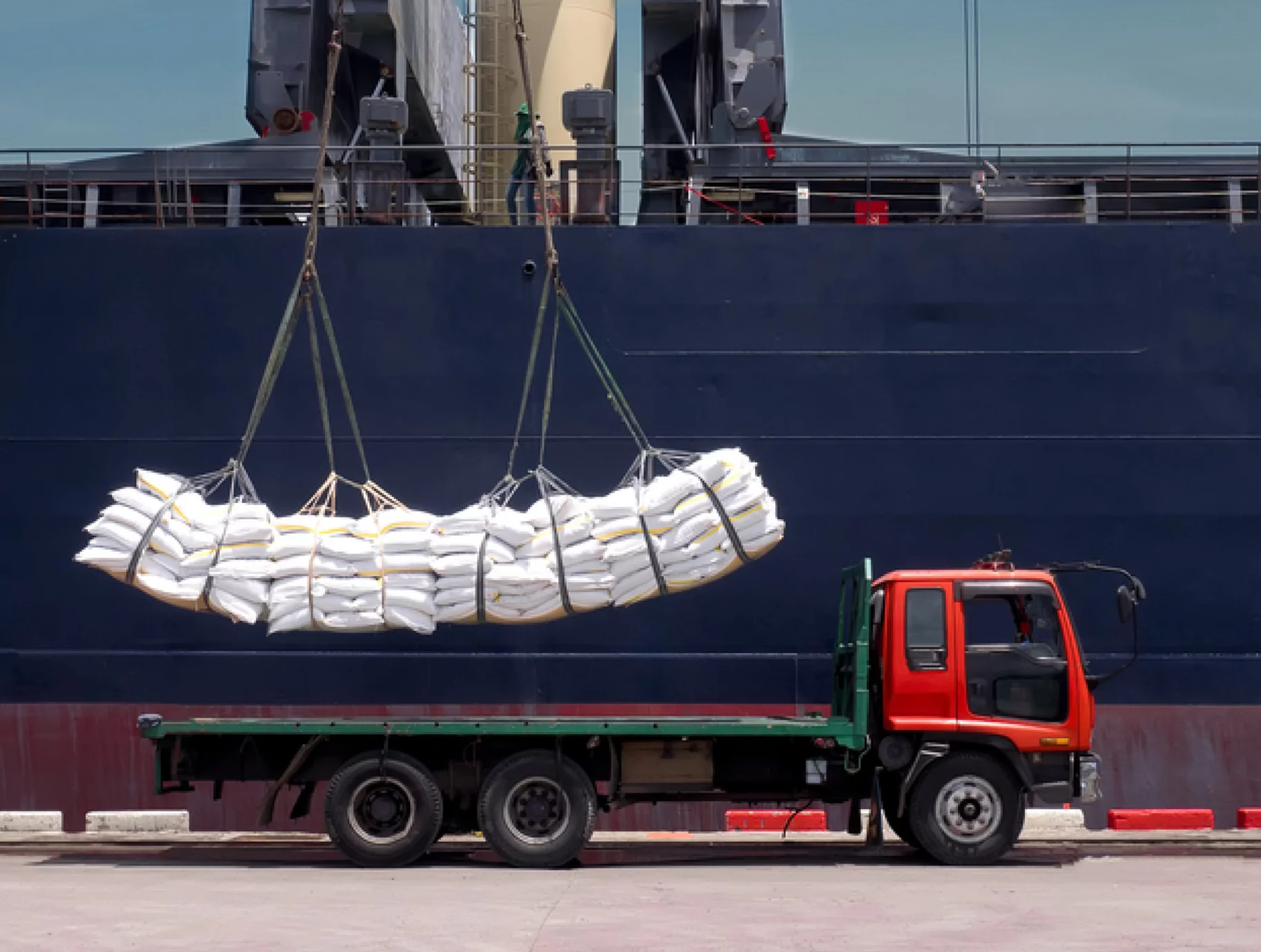 Bagged bulk cargo being lifted between a ship and a truck